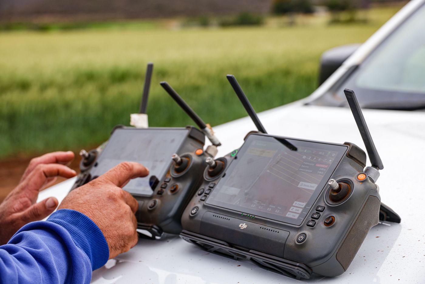 Pilot operating dual ground control stations on a vehicle hood in the field